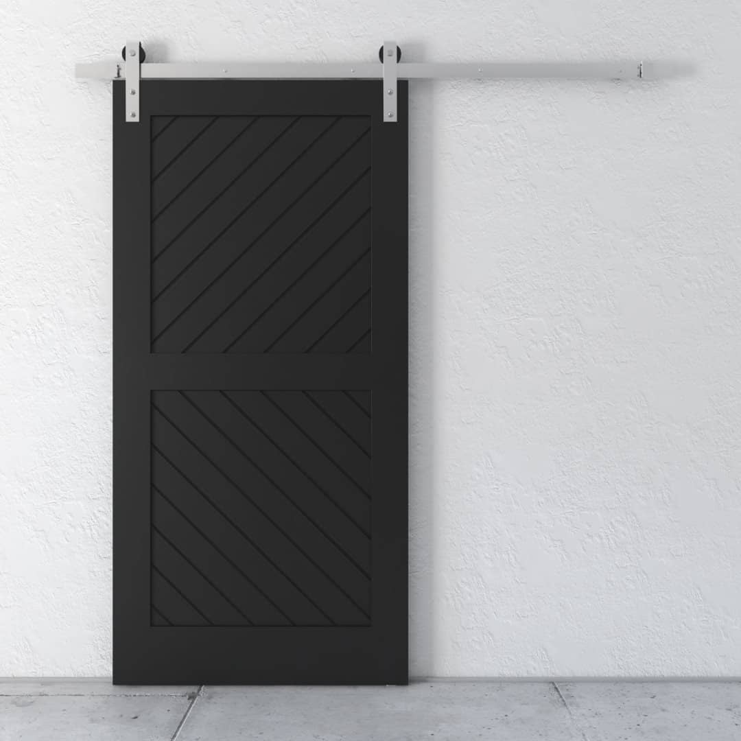 A black sliding barn door with a diagonal slatted pattern is mounted on a wall with a metal track system. The floor beneath is gray concrete.