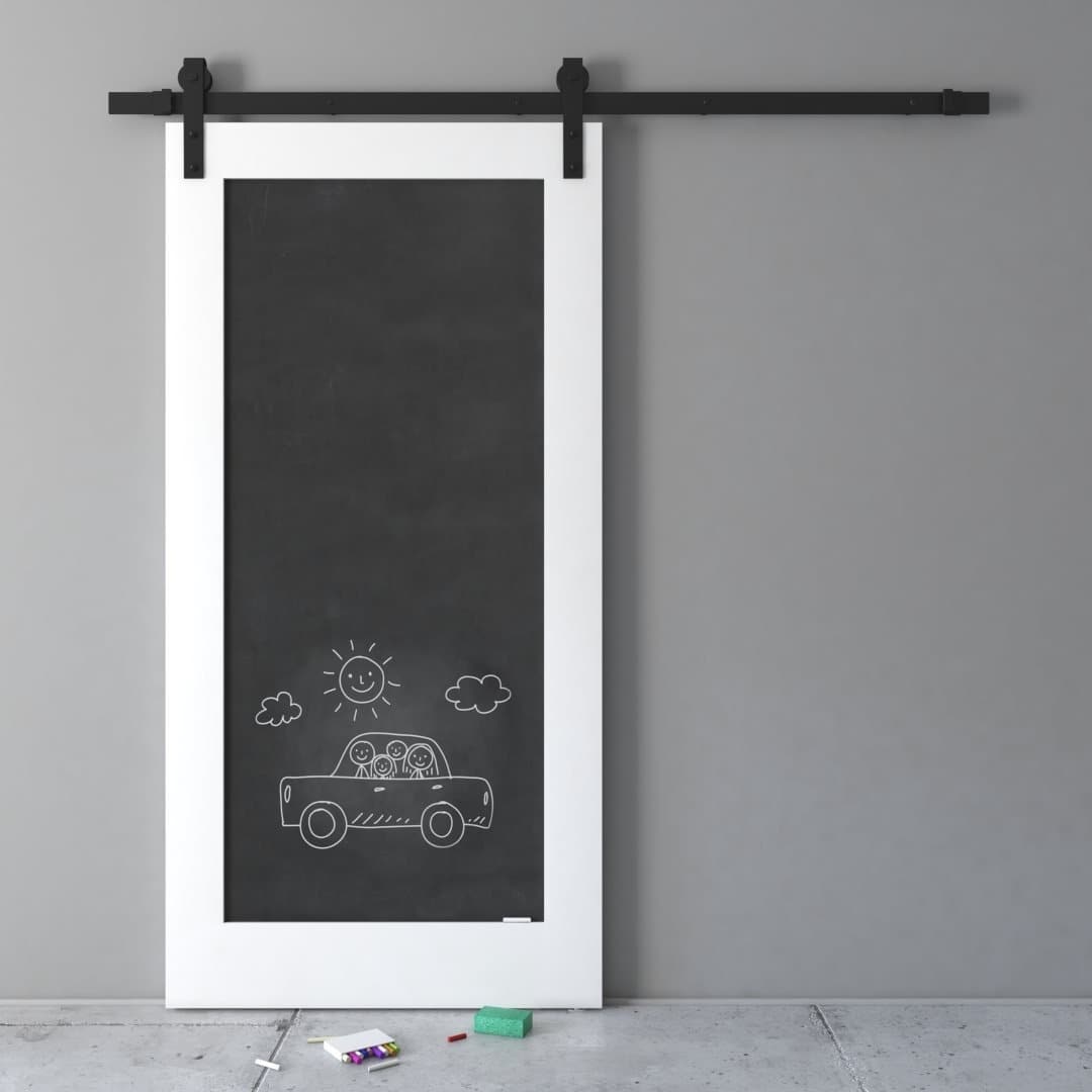 A black sliding door with a white frame features a chalk drawing of three people in a car with a sun and clouds above. Chalk pieces and a small eraser are on the floor below the door.