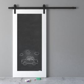 A black sliding door with a white frame features a chalk drawing of three people in a car with a sun and clouds above. Chalk pieces and a small eraser are on the floor below the door.