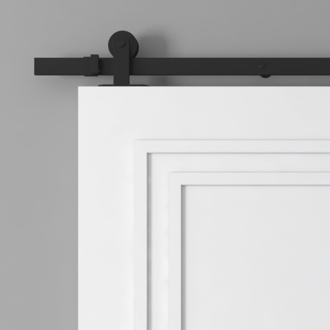 A close-up of the upper section of a white barn door with a black sliding hardware track mounted on a grey wall.
