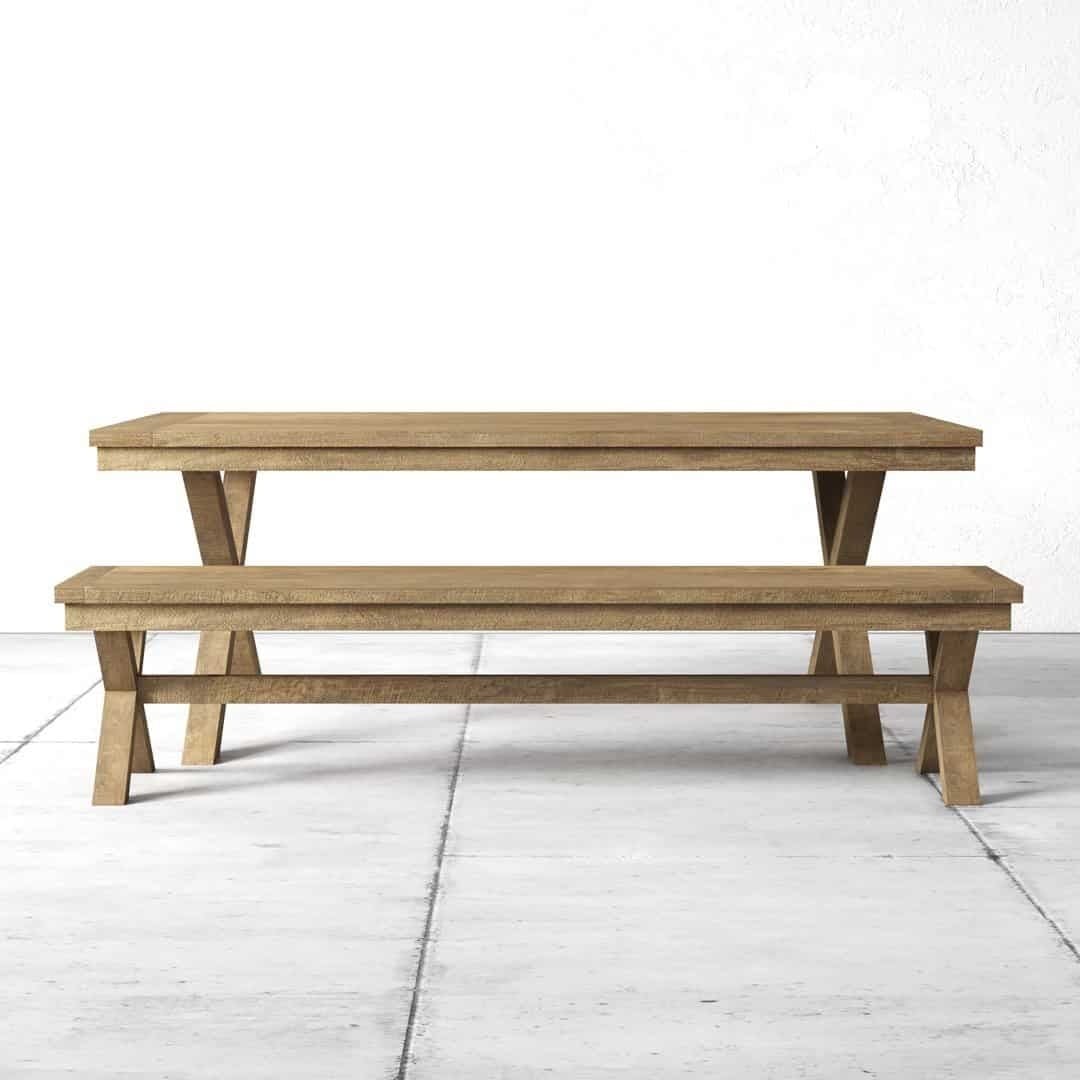 Wooden dining table and matching bench on a concrete floor against a white wall.