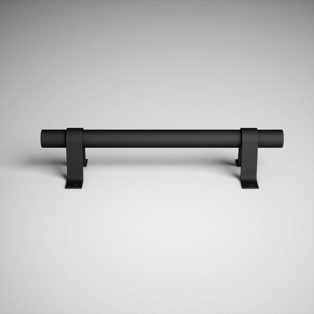The 13th Street Barn Door Handle, a sleek matte black horizontal bar, is mounted on two U-shaped brackets against a light gray background.