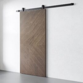 The Bianco Barn Door features a charming chevron pattern wood grain on a sleek metal rail system, perfectly complementing a white wall.