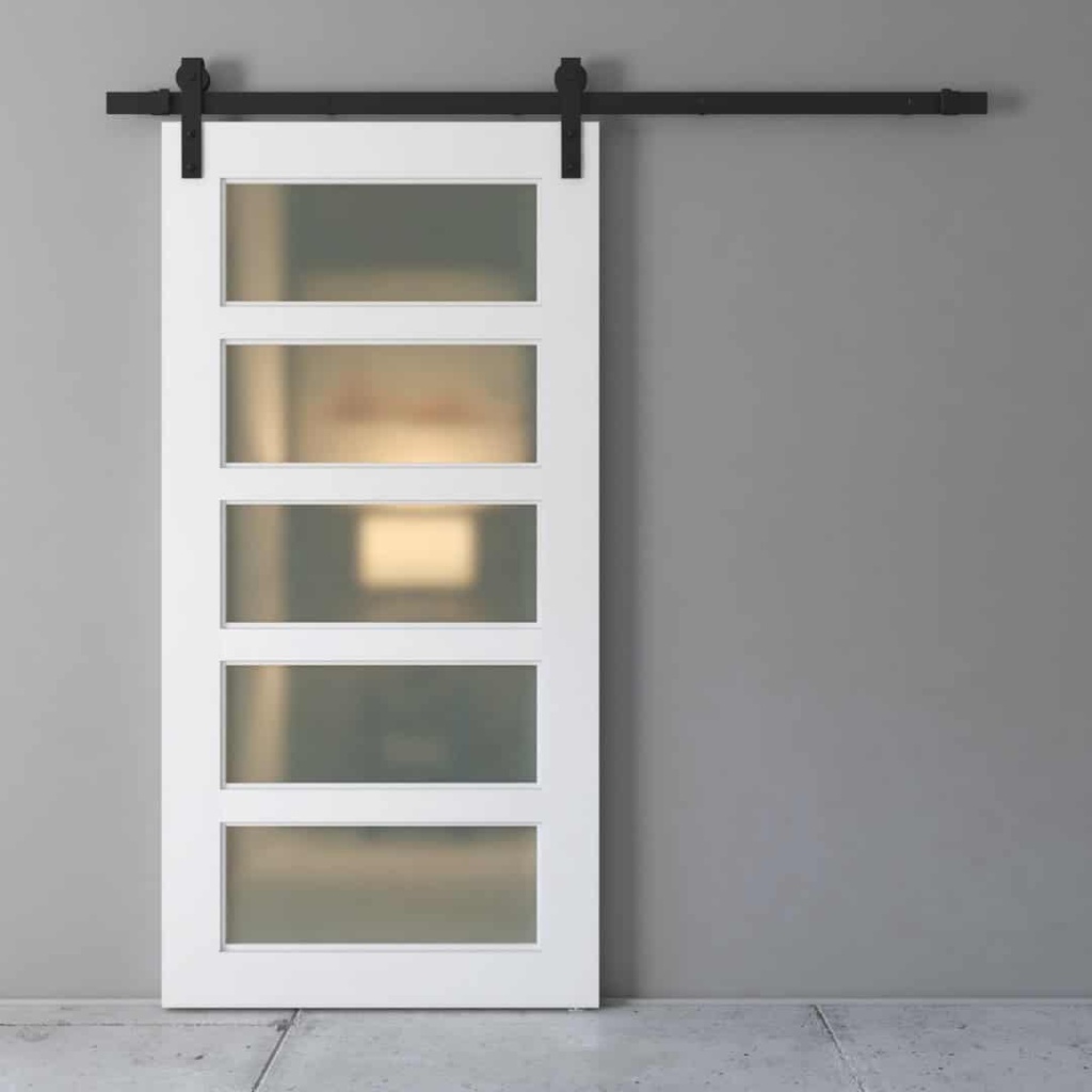 The Boston 5 Panel Barn Door, featuring white and frosted glass panels, is mounted on a black rail against a gray wall.