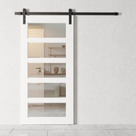 A white 5-panel sliding barn door with four glass panels, mounted on a black track, partially open to reveal a room with minimalistic decor.