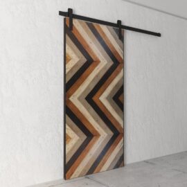 A Chevron 83" x 40" Barn Door featuring various wood finishes elegantly installed on a plain white wall.