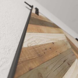 Close-up of the Herringbone 83" x 40" Barn Door with a metal track mounted on a white textured wall.