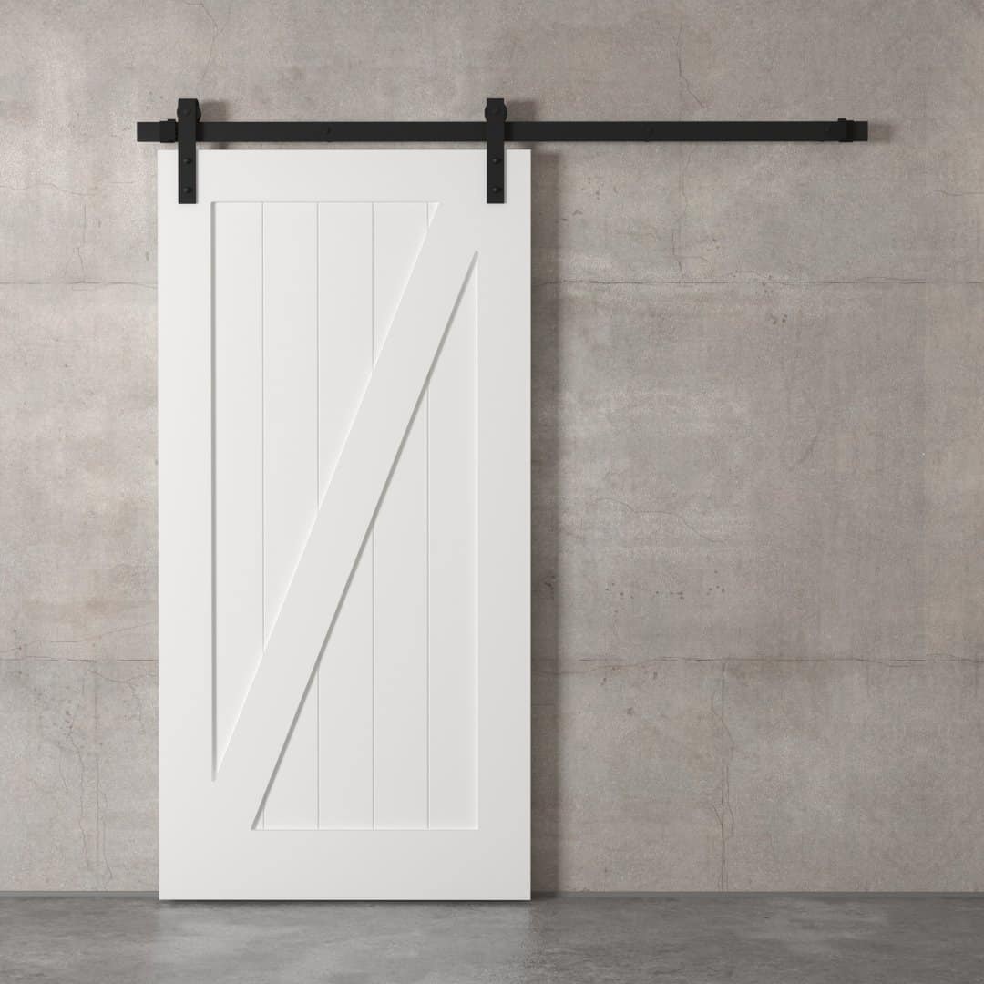 A Z-Panel Barn Door with black hardware is mounted on a plain gray concrete wall.
