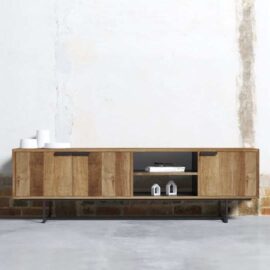 The 3 Door Parisian Factory 78″ TV Console, with a charming rustic finish, boasts three cabinets and two open shelves perfect for displaying small decorative items. It stands elegantly against a partially plastered white wall with a brick base.