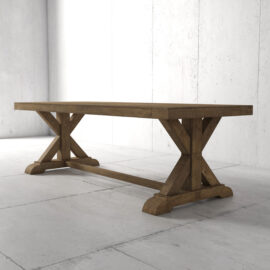The Madera Dining Table - Natural, featuring a wooden rectangular design with X-shaped supports, stands on a light gray tiled floor against a plain gray concrete wall.