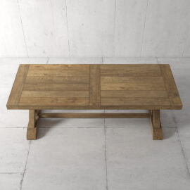 The Madera Dining Table - Natural, featuring a rectangular top and sturdy legs, stands on a white tiled floor. The table boasts a rustic finish and a simple design.