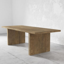 The Camden Dining Table with its rectangular wooden top and two wide, flat legs is set in a minimalist, white-walled room with a tiled floor.