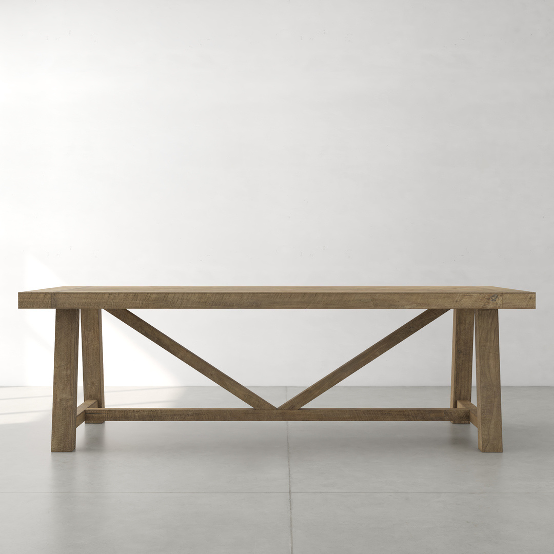 A Farmhouse Dining Table featuring a rectangular wooden top and X-frame support underneath, placed in a minimalistic room with a light-colored floor and wall.