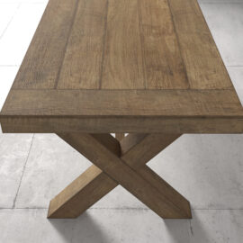 The Grand Cross Dining Table, featuring a rectangular wooden top and an X-shaped base, is placed on a tiled floor.