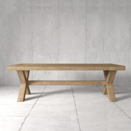 The Grand Cross Dining Table, featuring its distinctive X-shaped legs, stands in a minimalistic, grey-tiled room with a plain concrete wall backdrop.