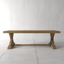 The Madera Dining Table - Natural, with its wooden rectangular tabletop and trestle base, stands on a tiled floor against a plain, white wall background.