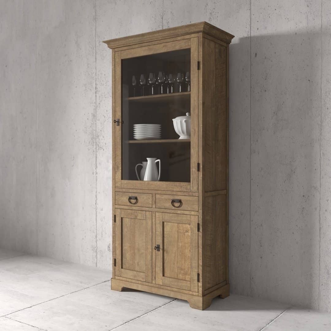Urban Woodcraft 36 Riverbend Display Consol – Natural (2) The Riverbend 36" Display Cabinet, made of wood and featuring glass doors, displays glassware and ceramic items on its shelves. It stands against a concrete wall and includes two drawers along with two closed compartments at the bottom.