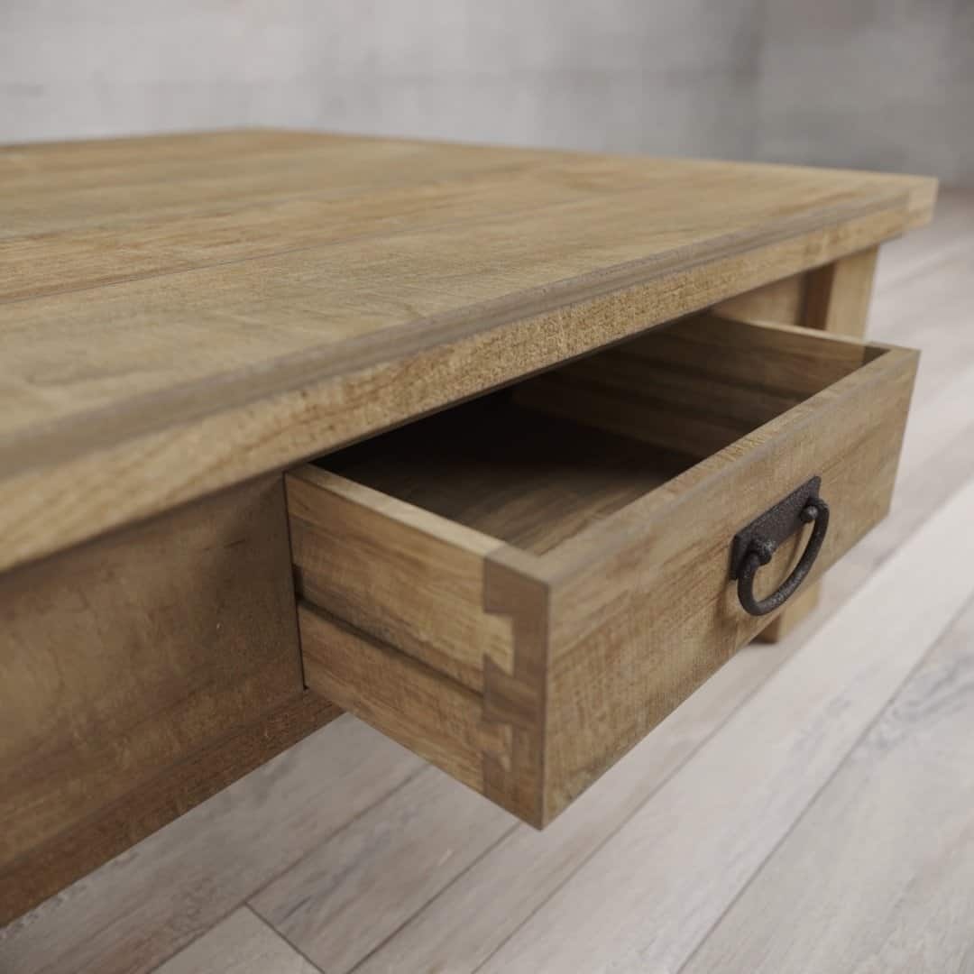 Urban Woodcraft 40 Riverbend Coffee Table - Natural (6) A close-up of the Riverbend Coffee Table with a drawer partially open, showcasing its dovetail joints and metal handle. The table features a natural wood finish with visible grain patterns.