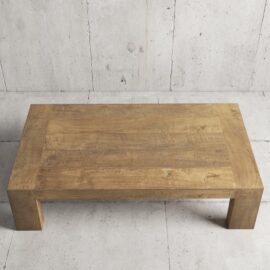 The Madison Coffee Table, a rectangular wooden piece with a simple and minimalist design, sits on a concrete floor.