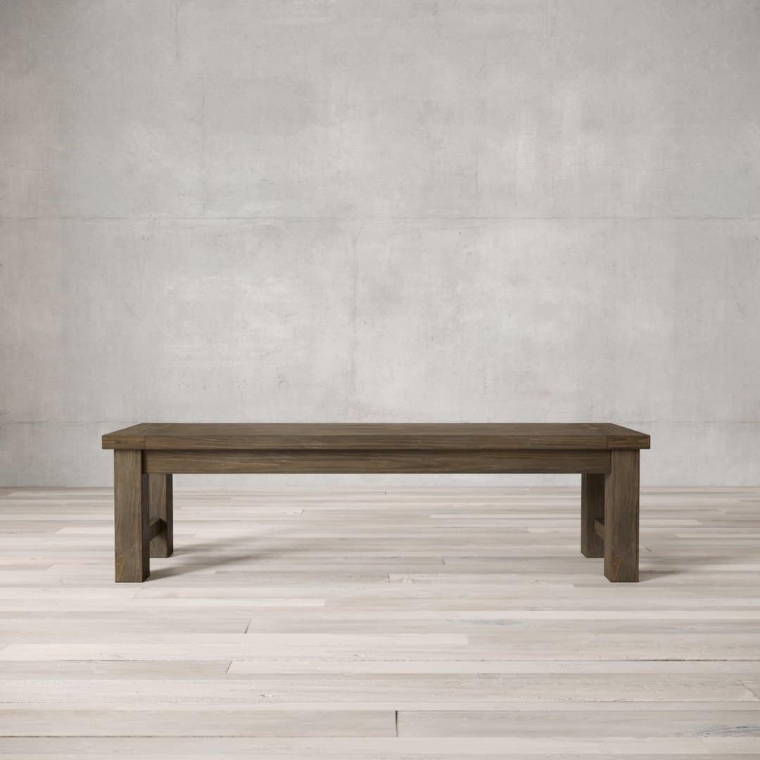 A straightforward, rectangular wooden Square Dining Bench with block legs stands on a light wooden floor against a plain, light grey concrete wall.