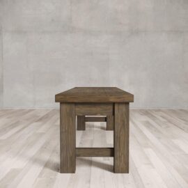 A square dining bench placed on a light-colored wooden floor against a concrete wall.