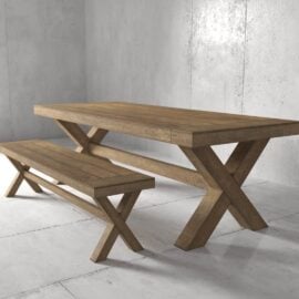 A dining set featuring the Grand X Dining Bench and an "X" shaped base wooden table, beautifully situated against a gray concrete wall and floor.