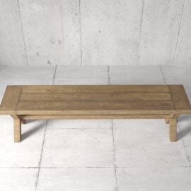 A rectangular Grand X Dining Bench with a natural finish sits on a tiled floor against a concrete wall background.