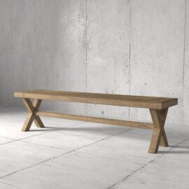 A Grand X Dining Bench placed against a plain concrete wall and tiled floor.
