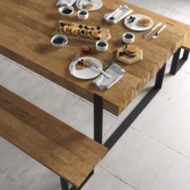 The Soma Dining Bench pairs perfectly with a wooden table set for breakfast. The setup includes plates of pancakes, bowls of berries, cups of coffee, and cutlery arranged neatly on a tiled floor.