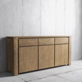 The Teca Dining Buffet with a natural finish stands against a concrete wall. It features three drawers on top and three cabinet doors below.