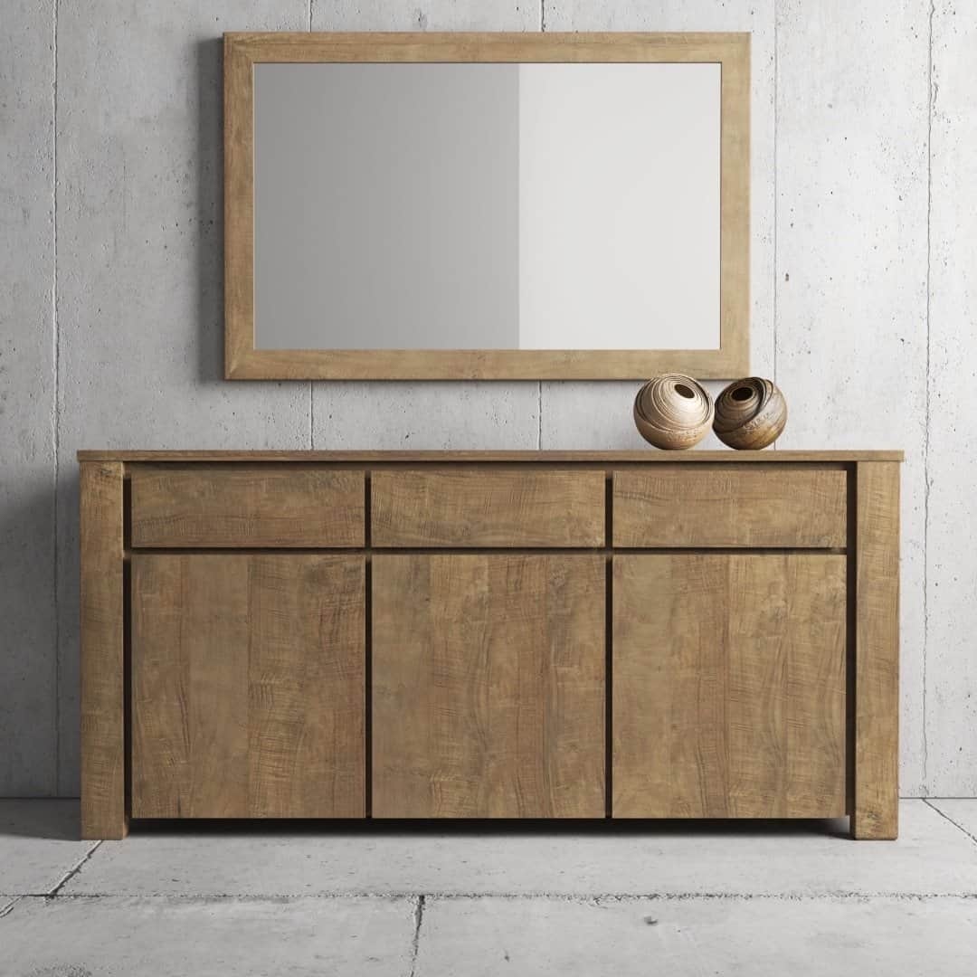 Urban Woodcraft 75 Teca Dining Buffet – Natural (7) The Teca Dining Buffet, which features three drawers and three closed compartments below, is placed against a concrete wall. An oblong mirror with a wooden frame hangs above the dining buffet. Two decorative vases sit on top.