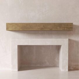 A minimalist fireplace with a beige rectangular opening and a light wooden wall mantel shelf mounted above it on a textured light-colored wall creates an inviting atmosphere in the Duluth home.