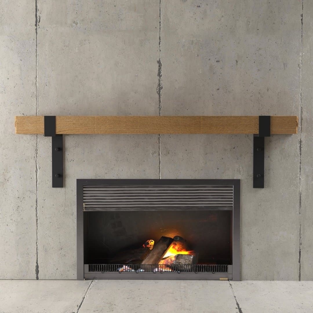 The Hudson Wall Mantel features a minimalist fireplace set against a modern concrete wall background, complete with a sleek wooden mantel. Inside the black-framed fireplace, a small fire burns gently.
