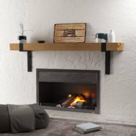A modern Hudson Wall Mantel showcases small decor items, including a book, a plant, and a vase. In front of the fireplace, a cushion and another book are neatly placed on the floor.