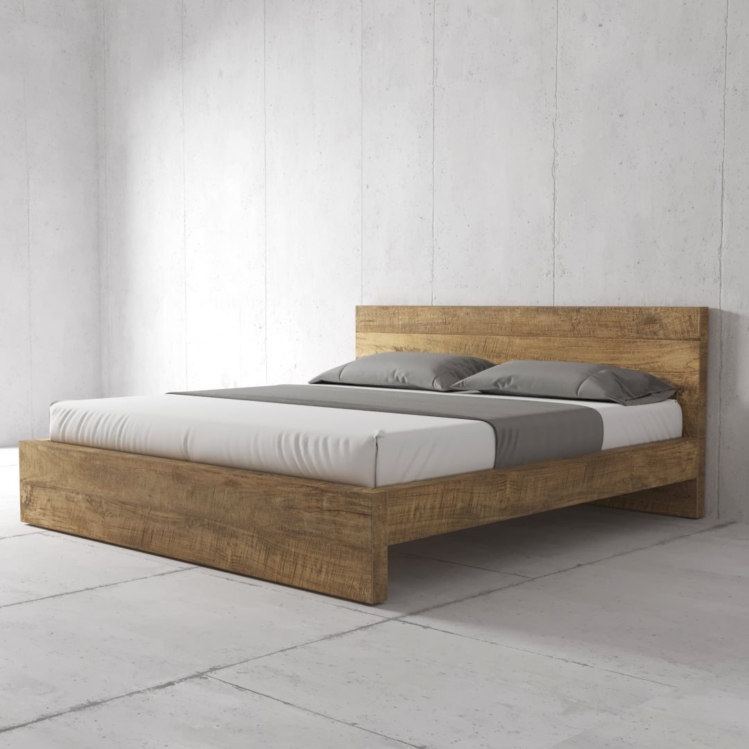A Lugano wooden bed frame with a mattress, white bed sheet, and two grey pillows, placed in a minimalist room with concrete walls and floor.