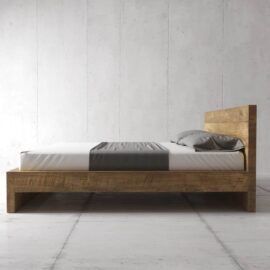 The Lugano Bed, featuring a minimalist wooden bed frame paired with a white mattress, complemented by a gray bed runner and pillows, stands against a plain, light-colored wall.