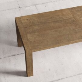 A close-up view of the Villa Dining Table in its natural finish, set against a light concrete background.