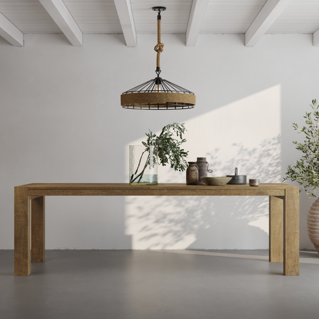 VILLA TABLE LIFESTYLE A minimalist room features the Villa Dining Table in natural wood adorned with decorative items, a hanging light fixture, and an olive tree plant against a white wall and concrete floor.