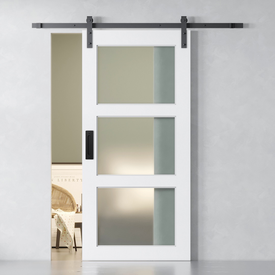 3-PANEL FROSTED GLASS 83″ X 40″ BARN DOOR (1) The 3-Panel Frosted Glass Barn Door partially reveals an interior room with a wicker chair and bookcase.