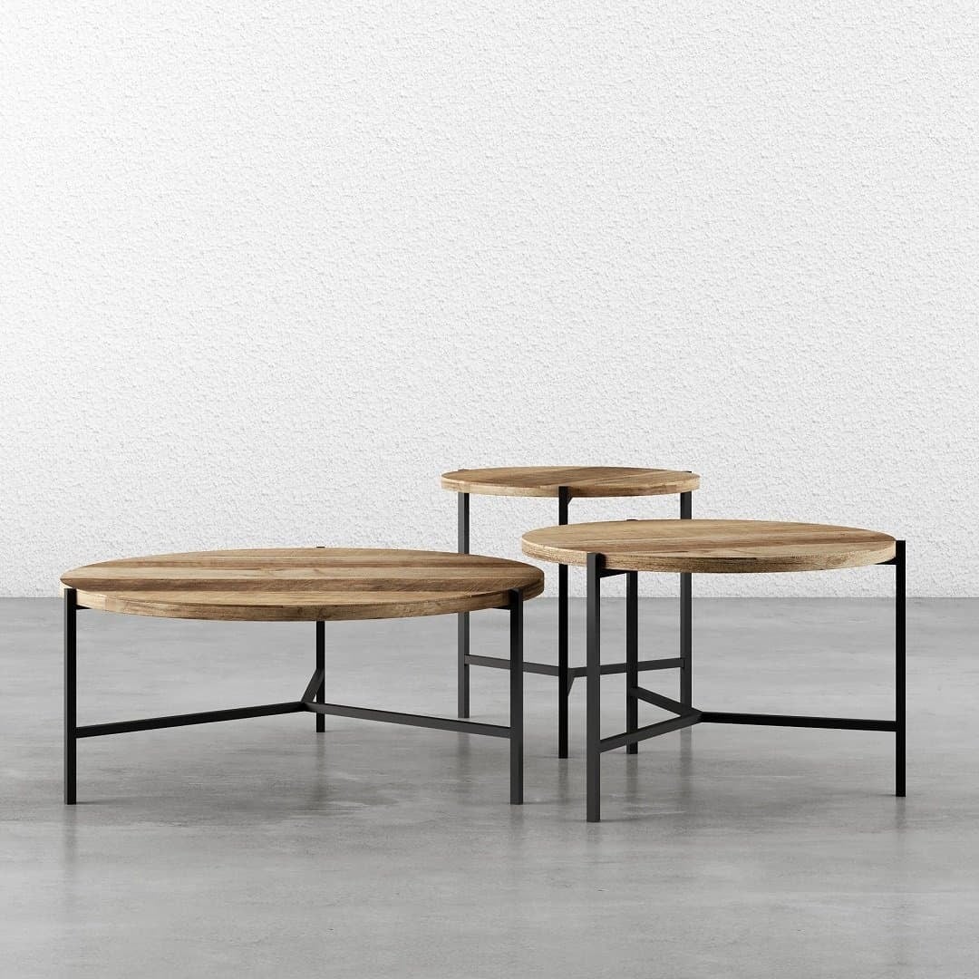 Three pieces of the 3-Piece Round Coffee Table with Star Legs, each at different heights, arranged closely together on a concrete floor against a plain white textured wall.