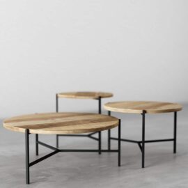 A 3-Piece Round Coffee Table with Star Legs, featuring three wooden tables of varying heights and black metal legs, arranged on a concrete floor.
