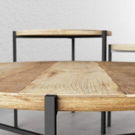 Close-up of two pieces from the 3-Piece Round Coffee Table with Star Legs set, showcasing the intricate wood texture and contemporary design. The tables are positioned on a light gray surface against a matching backdrop.