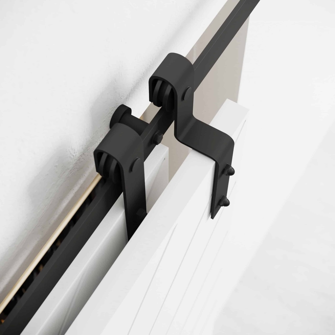 1 single track biparting (5) Close-up of the Single Track By-Pass black sliding door hardware attached to a white wall and door.