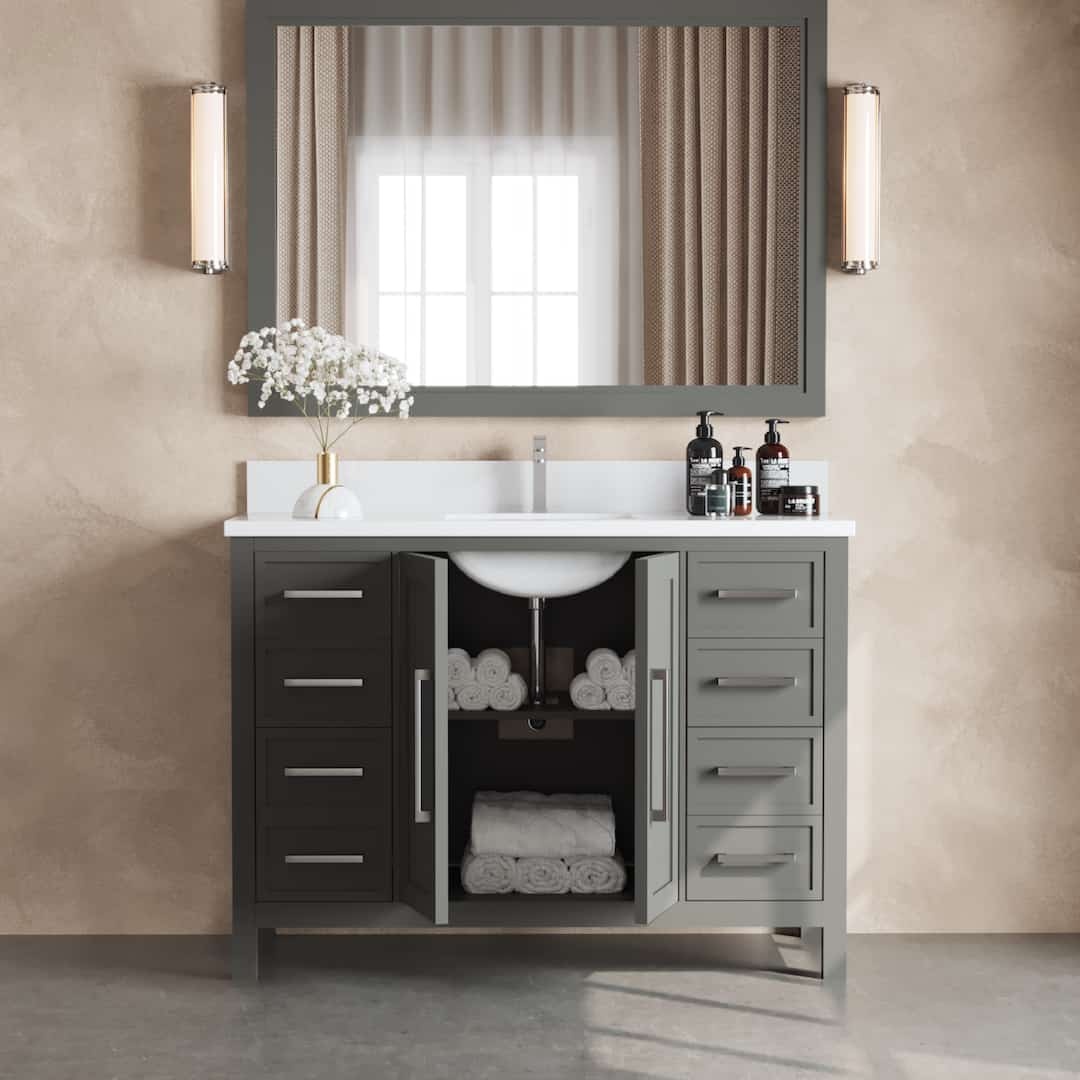 The Acadian 48" Single Bathroom Vanity with double doors open, revealing neatly stacked white towels. The countertop features a vase with white flowers, soap dispensers, and is complemented by a large mirror with wall lights on each side.