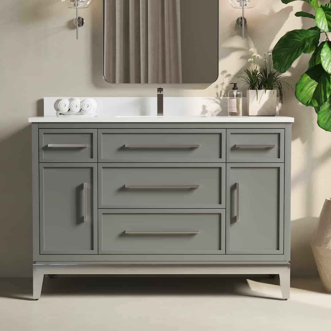 The Barrington 48" Single Sink Bathroom Vanity is a modern gray vanity featuring six drawers, an under-mount sink, a rectangular mirror, and decorative plants on the countertop.