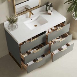 The Haldon 48" Single Sink Bathroom Vanity features a modern design with a white countertop, rectangular sink, brass faucet, gold-framed mirror, and six open drawers filled with toiletries. A green plant is placed on the right side for an added touch of freshness.