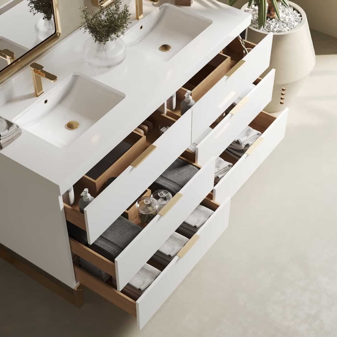 A Haldon 60" Double Sink Bathroom Vanity in white, featuring open drawers that display neatly arranged toiletries and towels, with a potted plant adorning the countertop.