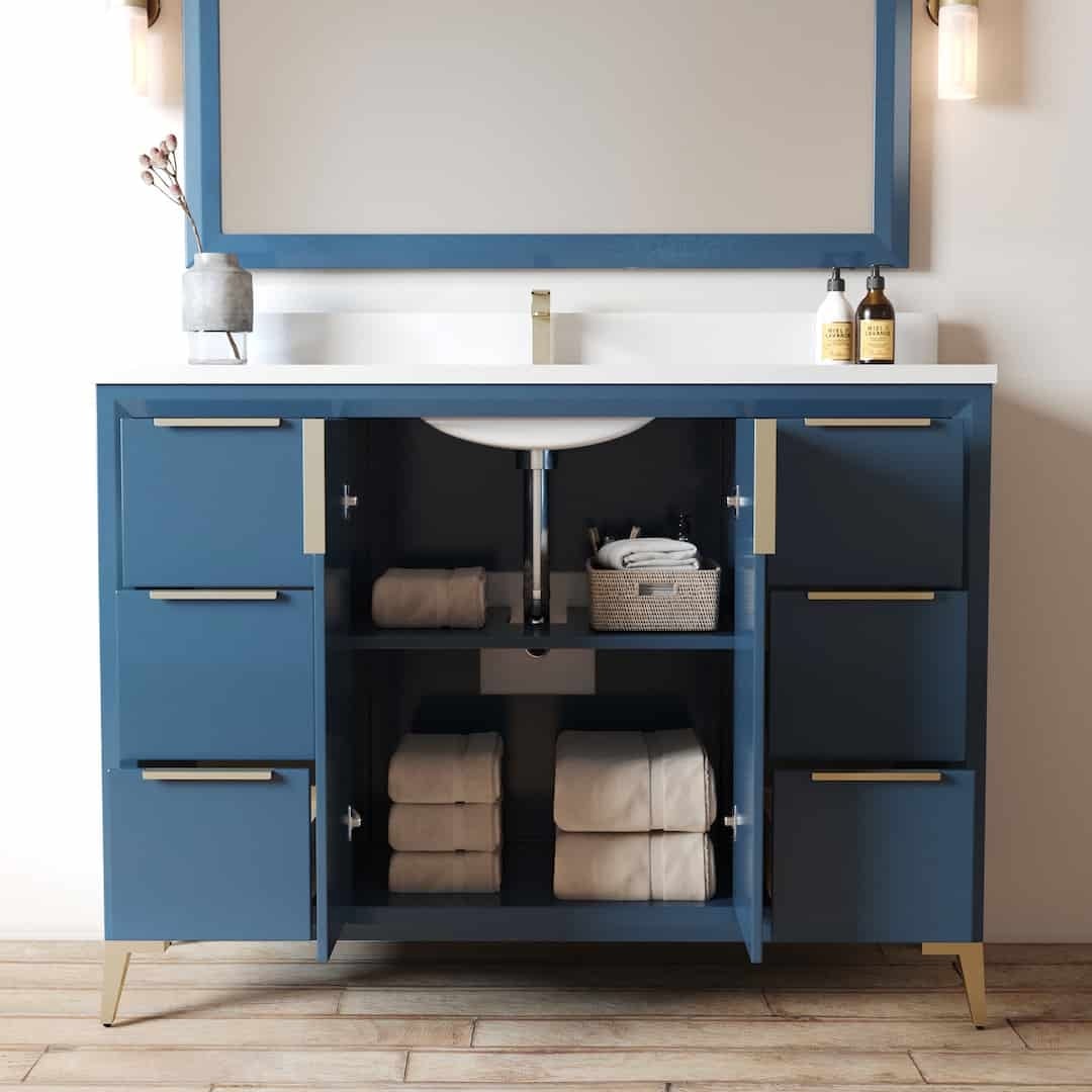 The Mendocino 48" Single Sink Bathroom Vanity in blue features open cabinets that neatly display folded towels and storage baskets below a pristine white countertop and sink, adorned with bottles and a vase on the counter.