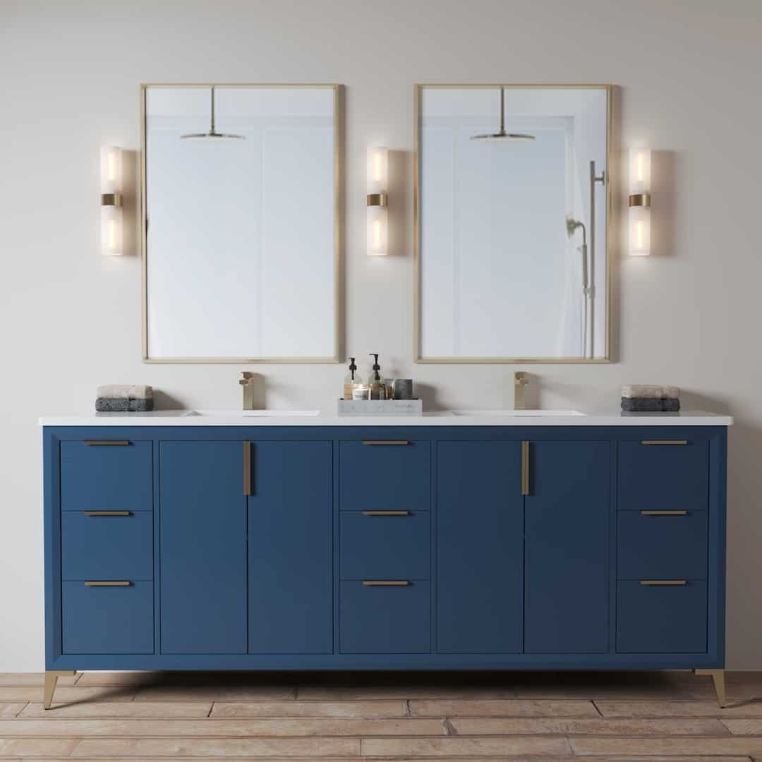 The Mendocino 72" Double Sink Bathroom Vanity features blue cabinets, two mirrors, and wall-mounted lights. The countertop is equipped with soap dispensers and folded towels, while the floor is adorned with wood.