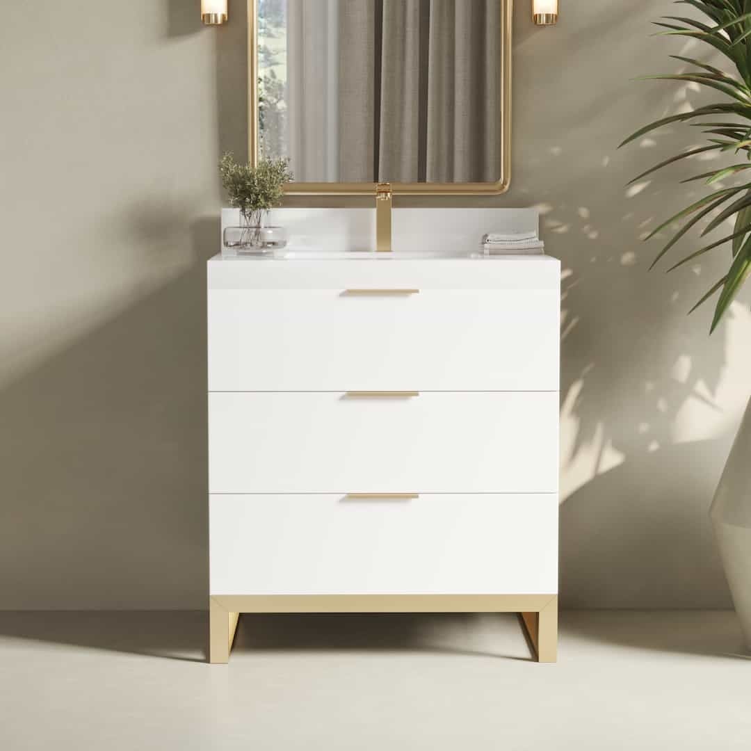 The Haldon bathroom vanity features a modern white design with three spacious drawers, complemented by a gold-framed mirror above and a potted plant on the right.